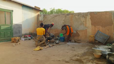 Rear-view-of-few-African-people-cooking-food-in-traditional-stove-on-a-sunny-day-in-Wulugu,-Ghana