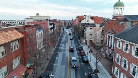 Rising-drone-shot-of-driving-vehicle-on-street-of-american-small-town