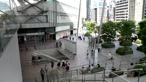 A-leisurely-paced-sequence-is-captured-while-descending-the-escalator-on-the-Yaesu-Entrance-side-outside-Tokyo-Station,-showcasing-the-modern-urbanity-of-city-life