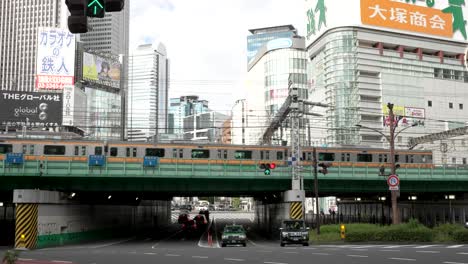 Tokio,-Japón,-La-Línea-Rápida-Chūō-Atraviesa-Vías-Elevadas-A-Través-Del-Bullicioso-Distrito-De-Shinjuku,-Pintando-Un-Cuadro-Diurno-Que-Resume-La-Vitalidad-De-La-Vida-Urbana-Moderna-En-Esta-Megaciudad.