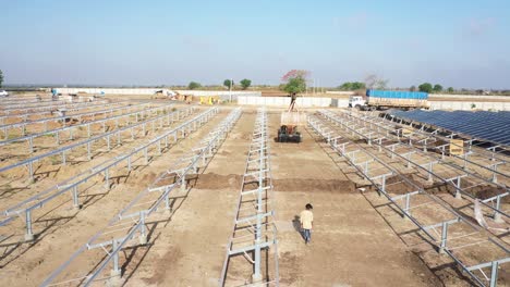 AERIAL-DRONE-VIEW-DOL-CAMERA-PASSING-AHEAD-WHERE-A-JCB-IS-PICKING-UP-A-LARGE-SOLAR-PANEL-BOX