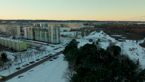 Twilight-over-a-suburban-edge-with-a-park-visible-beside-rows-of-apartment-blocks-in-a-snow-draped-setting,-exuding-calmness-in-the-cold-season---Gdańsk