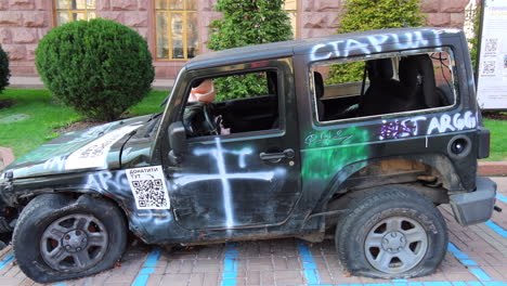 Shelled-black-car-on-Khreshchatyk-main-street-from-the-Russia-Ukraine-war-in-Kyiv-city-center,-destroyed-broken-jeep-war-vehicle-in-Ukraine,-4K-shot