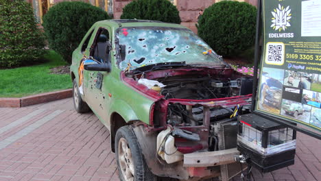 Shelled-green-car-on-Khreshchatyk-main-street-from-the-Russia-Ukraine-war-in-Kyiv-city-capital-center,-destroyed-war-vehicle-in-Ukraine,-4K-shot