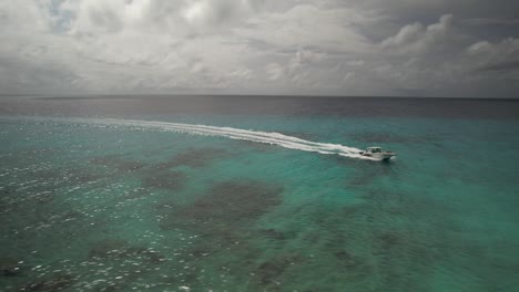 Lancha-Rápida-Navegando-Por-Aguas-Turquesas-De-Los-Roques,-Venezuela-Con-Nubes-Arriba,-Vista-Aérea