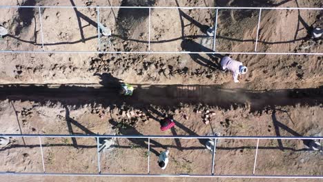 Aerial-drone-view-of-men-fitting-a-large-wire-supply-to-a-solar-system-and-lots-of-men-around