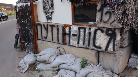 Concrete-defensive-position-fortress-with-sand-bags-and-camouflage-tarp-netting-on-a-road-in-Kyiv-Ukraine,-Russia-Ukraine-war,-Ukrainian-flag,-4K-shot