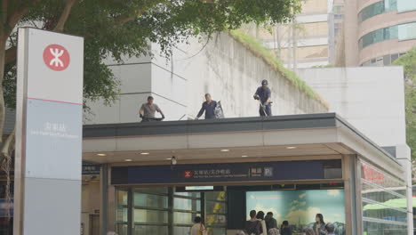 Workers-sweep-off-entryway-of-underground-transit-railroad-as-commuters-enter-station-below