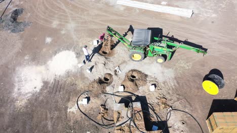 Vista-Aérea-De-Drones-Tractor-Cavando-Un-Pozo-Para-El-Suministro-De-Cables-Varios-Sistemas-Solares-Son-Visibles