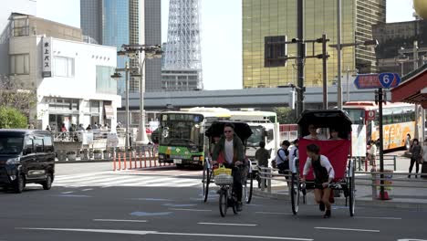 Conductor-De-Rickshaw-Arrastrando-A-Turistas-A-Través-Del-Paso-De-Peatones-En-Asakusa