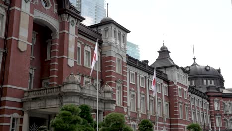 Ikonisches-Gebäude-Mit-Seiner-Klassischen-Fassade-Des-Bahnhofs-Im-Einkaufsviertel-Marunouchi-In-Chiyoda,-Tokio,-Japan,-Umgeben-Von-Flaggen