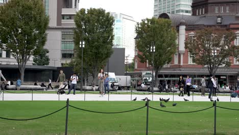 Marunouchi-Square-surrounded-by-its-buildings,-skyscrapers-and-parks-in-the-Marunouchi-shopping-district-in-Chiyoda,-Tokyo,-Japan,-with-the-esplanade-crowded-with-people