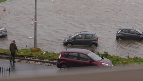 Coche-Pequeño-Marcha-Atrás-Intentando-Salir-Del-Aparcamiento-Inundado