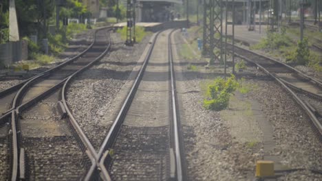 Train-conductor's-view-approaching-a-station,-people-waiting,-sunny-day