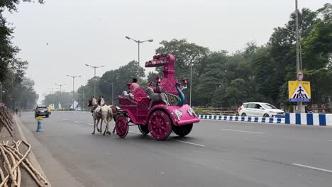 Vista-De-Perfil-De-Un-Carro-De-Caballos-Rosa-En-La-Carretera-Roja-En-Calcuta-Durante-El-Día