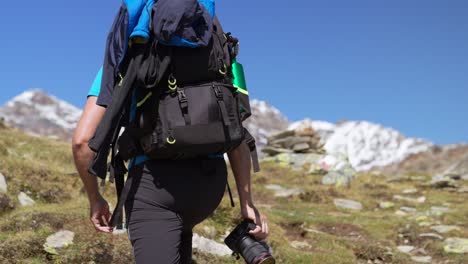 Un-Hombre-En-Cámara-Lenta-Con-Mochila-Y-Cámara-Sube-Hacia-Los-Picos-De-Las-Montañas-En-Un-Día-Soleado