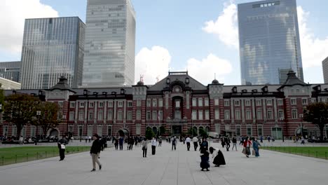 Edificio-Icónico-Y-Clásico-De-La-Estación-De-Tren-En-El-Distrito-Comercial-De-Marunouchi-En-Chiyoda,-Tokio,-Japón,-Con-La-Explanada-Llena-De-Gente-Con-Máscaras