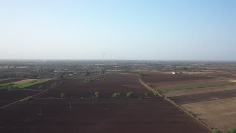 Luftdrohnenkamera-Bewegt-Sich-Vorwärts,-Wo-Viele-Windmühlen-Und-Traktoren-Auf-Dem-Feld-Laufen