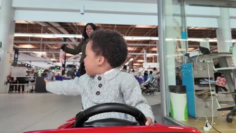 3-year-old-black-kid-riding-an-electric-toy-car-inside-a-Mall-in-valencia,-Spain