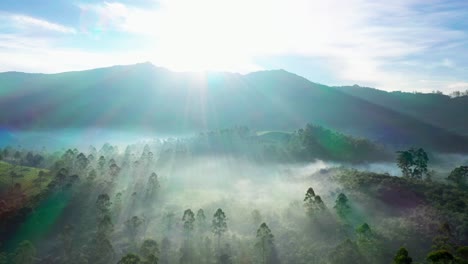 Vista-Aérea-De-Drones-Rayos-De-Sol-Super-Cayendo-Detrás-De-La-Montaña-Y-La-Niebla-Es-Visible