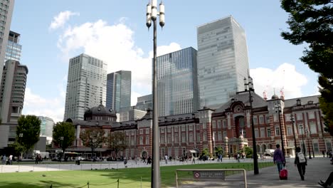 Estación-De-Tokio-Rodeada-De-Sus-Edificios,-Rascacielos-Y-Parques-En-El-Distrito-Comercial-De-Marunouchi-En-Chiyoda,-Tokio,-Japón,-Con-La-Explanada-Llena-De-Gente.