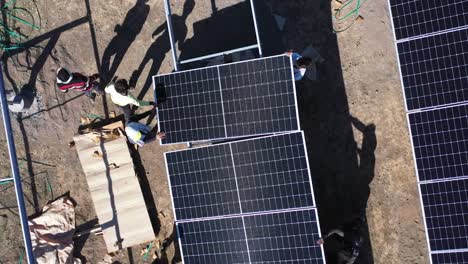 Vista-Aérea-De-Drones-De-Hombres-Instalando-Paneles-Solares-En-Línea-Y-Suministrando-Cables