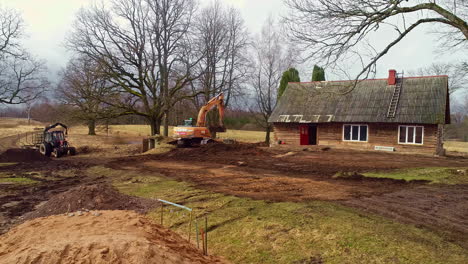 Excavator-reshapes-earth-near-house,-leveling-for-future-development,aerial-view