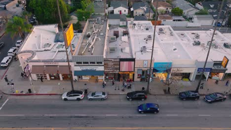 Drone-Hovering-Over-Busy-Studio-City-Hot-Spot,-Shoppers-Enjoying-Ice-Cream-and-Walking-on-Sunny-Los-Angeles-Day