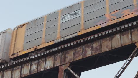 Auto-Carrier-Train-Covered-in-Graffiti-Crosses-an-Old,-Rusty-Railroad-Trestle-at-Sunset