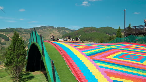 People-Ride-Tubes-on-Dry-Slide-At-Mongo-Land-in-Da-Lat,-Vietnam-in-Tracking-Slow-Motion