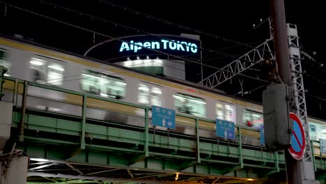 JR-Chuo-Line-glides-across-an-elevated-rail-in-the-Shinjuku-district-of-Japan,-unveiling-the-nocturnal-charm-of-the-cityscape