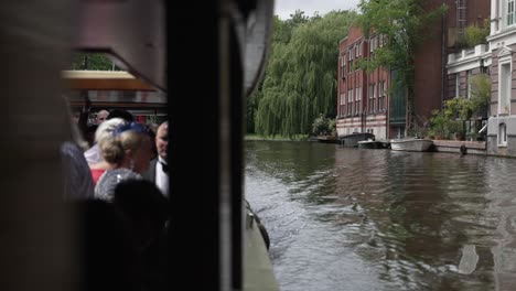 Montar-En-Un-Barco-A-Través-Del-Paisaje-Urbano-De-Ámsterdam,-Países-Bajos,-Debajo-De-Un-Puente-Que-Muestra-El-Paisaje-Histórico-Como-Forma-Tradicional-De-Transporte-En-El-Agua.