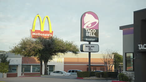 Plano-Medio-De-Carteles-De-Taco-Bell-Y-Mcdonald&#39;s-Con-Logotipos-Afuera-De-Restaurantes-De-Cadenas-De-Comida-Rápida