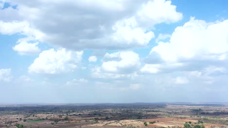 Zeitraffer-Drohnenkamera-Aus-Der-Luft,-Die-Viele-Wegblasende-Wolken-Und-Große-Felder-In-Der-Umgebung-Zeigt