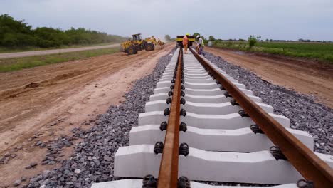 Eisenbahnarbeiter-Verlegen-Schwellen,-Schotter-Und-Unterbau,-Während-Sie-Schienenschwellen-Befestigen,-Rückzug-Aus-Der-Luft