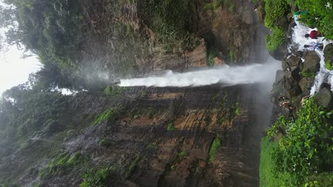 Vertikal:-Touristen-Erkunden-Den-Schroffen-Fuß-Des-üppigen-Karas-Biru-Wasserfalls