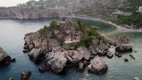 Drone-orbiting-around-Isola-Bella-island-near-Taormina-coast-at-sunset