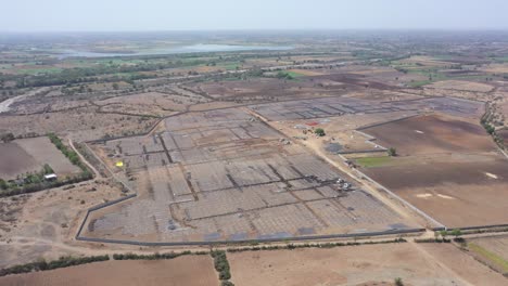 El-Dron-Aéreo-Se-Mueve-Hacia-La-Vista-Donde-Se-Ve-Una-Gran-Granja-Solar-En-Medio-De-Muchos-Campos-Alrededor