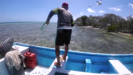 Hombre-Pescando-Desde-Un-Barco-En-Aguas-Cristalinas-Cerca-De-Manglares,-Día-Soleado