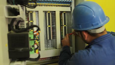 Ein-Männlicher-Elektriker-Verwendet-Im-Werk-Sorgfältig-Einen-Schraubenzieher-In-Der-Schalttafel