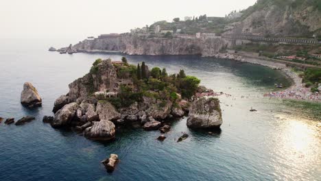 Drone-orbiting-around-Isola-Bella-island-near-Taormina-coast-at-sunset