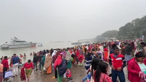 Wide-shot-of-Hindus-taking-religious-bath-in-Babughat,-Kolkata-for-the-celebration-of-Sankranti-festival-during-evening