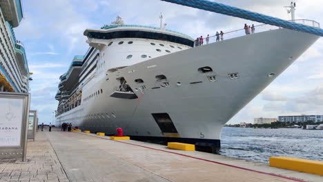 Amid-the-pier's-hustle,-determined-group-of-individuals-pulls-hefty-mooring-line,-securing-massive-cruise-ship-with-teamwork-and-precision-|-Group-of-people-pulling-heavy-mooring-line-of-Ship