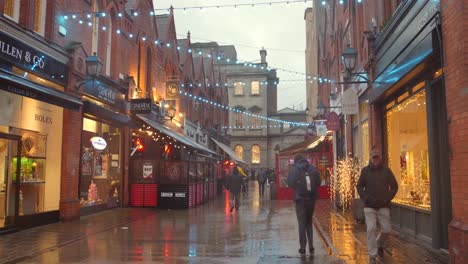 Vista-De-Perfil-De-Una-Calle-De-Dublín-Con-Tiendas-Y-Puestos-A-Ambos-Lados-Y-Decorada-Con-Luces-Durante-Una-Tarde-Húmeda-En-Irlanda