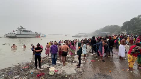 Side-wide-angle-view-of-Hindus-bathing-in-Babughat,-Kolkata-for-the-celebration-of-Sankranti-festival-during-evening-