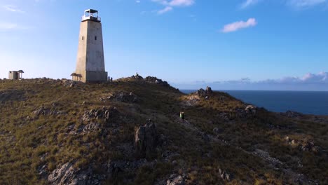 A-solitary-lighthouse-on-a-rocky-hill-along-the-venezuelan-coast,-blue-sky,-aerial-view