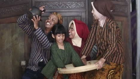 A-happy-Javanese-family-couple-with-their-two-children-with-an-earthen-jug,-Central-Java,-Indonesia