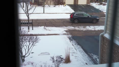 Coche-Que-Sale-En-La-Carretera-Con-Nieve-Vista-Desde-La-Ventana-De-La-Casa-En-Cámara-Lenta-De-Alto-ángulo