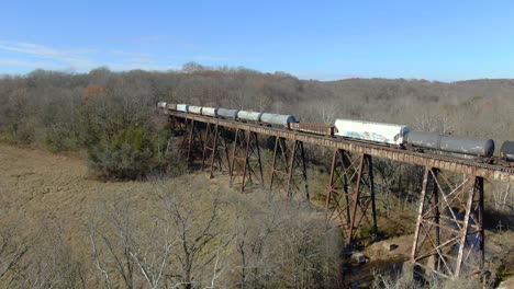 Toma-Aérea-Empujando-Hacia-Un-Tren-De-Carga-Mixto-Que-Cruza-El-Caballete-Pope-Lick-En-Kentucky-Durante-El-Invierno