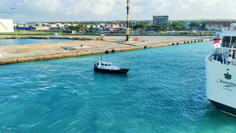 Awaiting-the-cruise-ship's-departure,-pilot-boat-stands-ready-near-the-port,-ensuring-safe-navigation-and-assisting-in-the-vessel's-smooth-exit